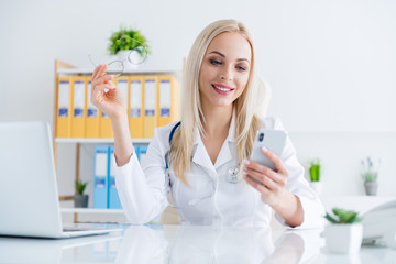 Close-up portrait of her she nice attractive pretty confident cheerful girl doc cardiologist surgeon therapist giving advice using cell app consulting in modern light white workplace workstation
