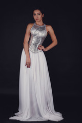 Fototapeta premium Pretty girl posing in a fashion dress over black background