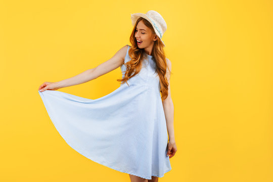 young girl in a summer hat, dressed in summer clothes, smiling on an isolated yellow background