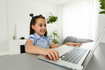 Pretty stylish schoolgirl studying homework math during her online lesson at home, social distance during quarantine, self-isolation, online education concept, home schooler