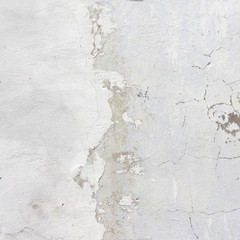 the white wall of an old house with beautiful cracks from time. white paint and whitewash on the wall. the background is white with soft blue and yellow. white old wall background