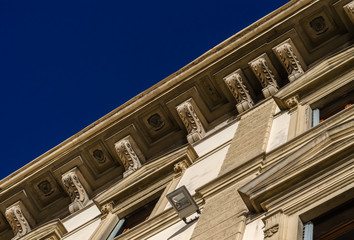 Decorated structural stone corbels in a row under the roof of beautiful italian old palace