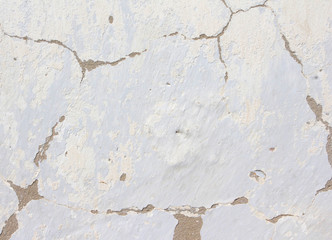 the white wall of an old house with beautiful cracks from time. white paint and whitewash on the wall. the background is white with soft blue and yellow. white old wall background