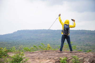 man with backpack stand on the top of the mountain And raised his hand to be happy in his success