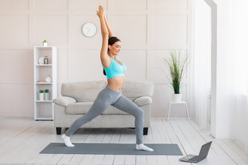 Woman Training Exercising At Laptop Standing In Yoga Pose Indoors
