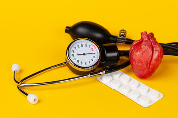 Heart and mechanical blood pressure monitor on yellow background. Measurement and control of blood...