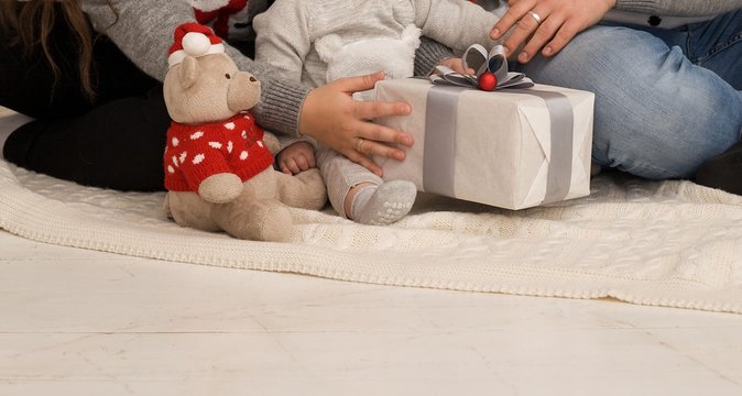 Family photo, baby, mom and dad. In the hands of a gift and a teddy bear. New Year photo session