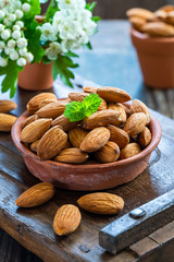 Fresh almonds in a ceramic pot on wooden table