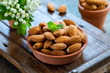 Fresh almonds in a ceramic pot on wooden table