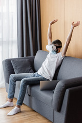 Man in medical mask and vr headset sitting on couch at home