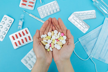 The doctor's hands are holding pills. cure for coronavirus. Medical remedies in the fight against covid-19. Pills, syringes, thermometer, medical mask on blue table. conceptual medical background.