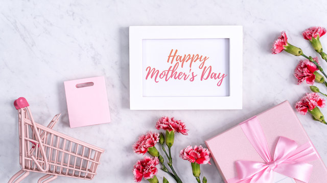 Happy Mother's Day background design concept with greeting words, beautiful pink, red carnation flower bouquet on marble table, top view, flat lay, copy space.