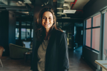 Smiling female executive in her office - obrazy, fototapety, plakaty
