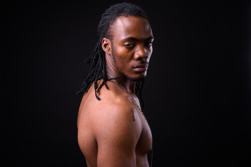 Face of young handsome muscular African man with dreadlocks shirtless