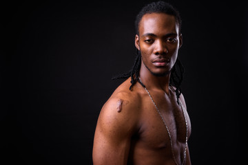 Face of young handsome muscular African man with dreadlocks shirtless