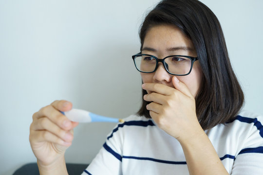 Asian girl holding a thermometer Check the body temperature by yourself. The concept of medical care to patients at home healthcare by yourself.