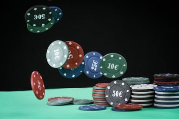 Poker playing chips on a green table and black background. Online gambling. Addiction. Falling poker chips