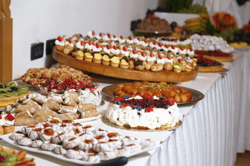 buffet with sweets. fruits and other sweets on dessert table. Rows of tasty looking desserts in beautiful arrangements. Sweets on banquet table - picture taken during catering event