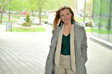 Photo portrait of a young business woman blonde smiling posing on a background of a city outdoors