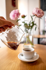 Black filter coffee on the table in cafe service kettle hario pour over cup flowers