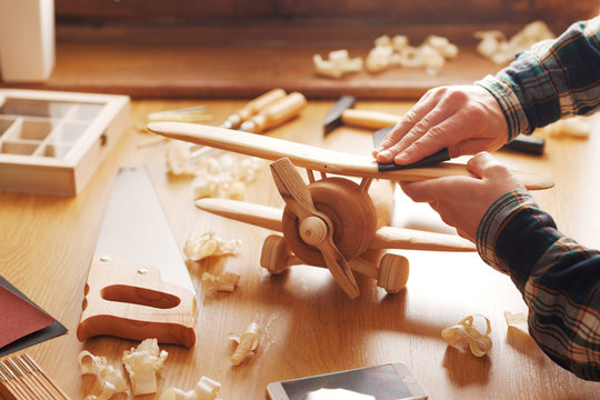 Craftsman building a wooden toy airplane