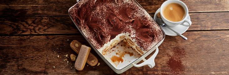 Dish of tiramisu with portion missing and coffee