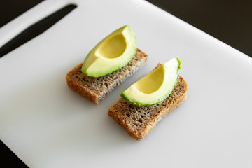Avocado on a plate. White plate with avocado cut in half and bread.