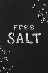 Inscription salt free, made of coarse sea salt on black background.