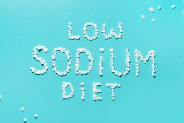 The concept of a low sodium diet. Prevention of hypertension and heart disease. Salt crystals on blue background.