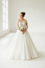 bride in white wedding dress. happy beautiful young woman in white traditional wedding dress on white background. big windows and white walls.