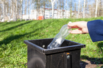 Close up hand throwing empty plastic bottle into the trash
