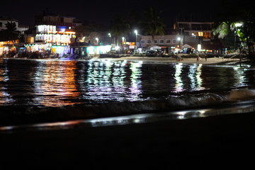 Fototapeta na wymiar City lights are reflected in the surf on the beach in Sri Lanka.