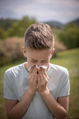 Allergy attack in nature,  boy suffering with pollen allergy sneezing.
