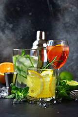 Three classic cocktails : aperol spritz, mojito and lemon cooler with rosemary with ingredients for...