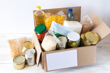 Cardboard box with oil, canned food, cereals and pasta.