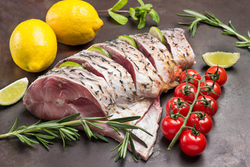 Fresh river fish on a metal tray. Lemon and sprig of cherry tomato and rosemary.
