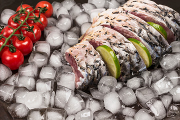 Fresh river fish on melting ice. Lemon and sprig of cherry tomato.