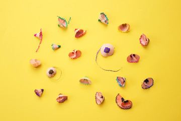 Color pencils shavings on yellow as creative background. Back to school concept