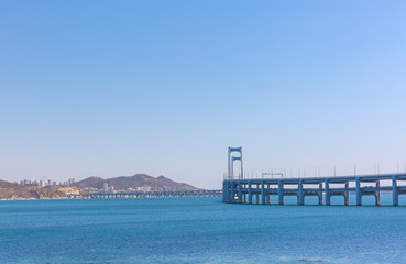 Obraz premium Black stone and city cross-sea bridge in the sea in Dalian, Liaoning, China in the morning