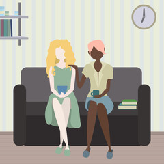 Girlfriends discuss what they saw on the phone while sitting nearby on the couch..Two girls, girlfriends, discuss what they have read or seen on the phone and have fun spending time.