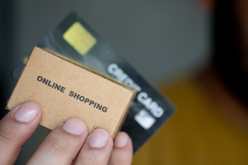 Hands holding credit card and miniature brown cardboard box online shopping.