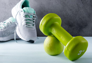 1 green dumbbell,  Apple, gray sneakers on a gray