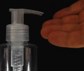 An antiseptic bottle dispenser is used for a hand on a black background. Bottle of hand sanitizer. Coronavirus disinfectants, Covid19 disinfectants