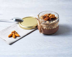 healthy breakfast of chocolate, oatmeal and nuts on a light wooden background