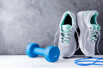 gray sneakers  , 1 blue dumbbell, skipping rope, on a gray