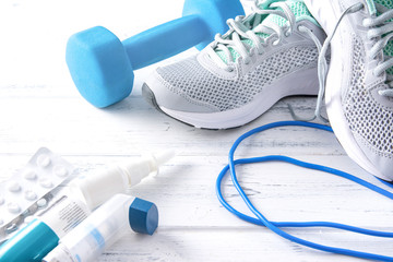 grey sneakers, blue dumbbell, medication on a white background