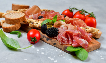 food flat lay italian  antipasti prosciutto, salami, bresaola olives tomatoes and grissini bread sticks. aperitif happy hour