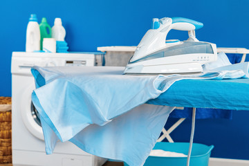 Housekeeping concept. Washing machine and ironing board close up