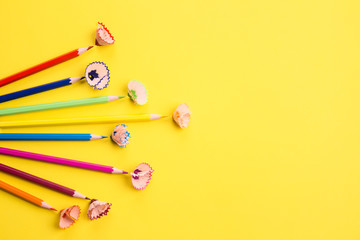 Color pencils and shavings on yellow as creative background with copyspace. Back to school concept