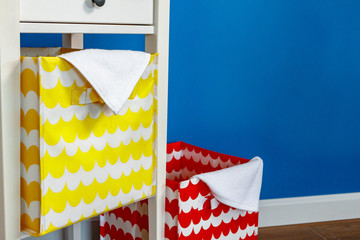 White wooden nightstand with storage box against blue wall, close up